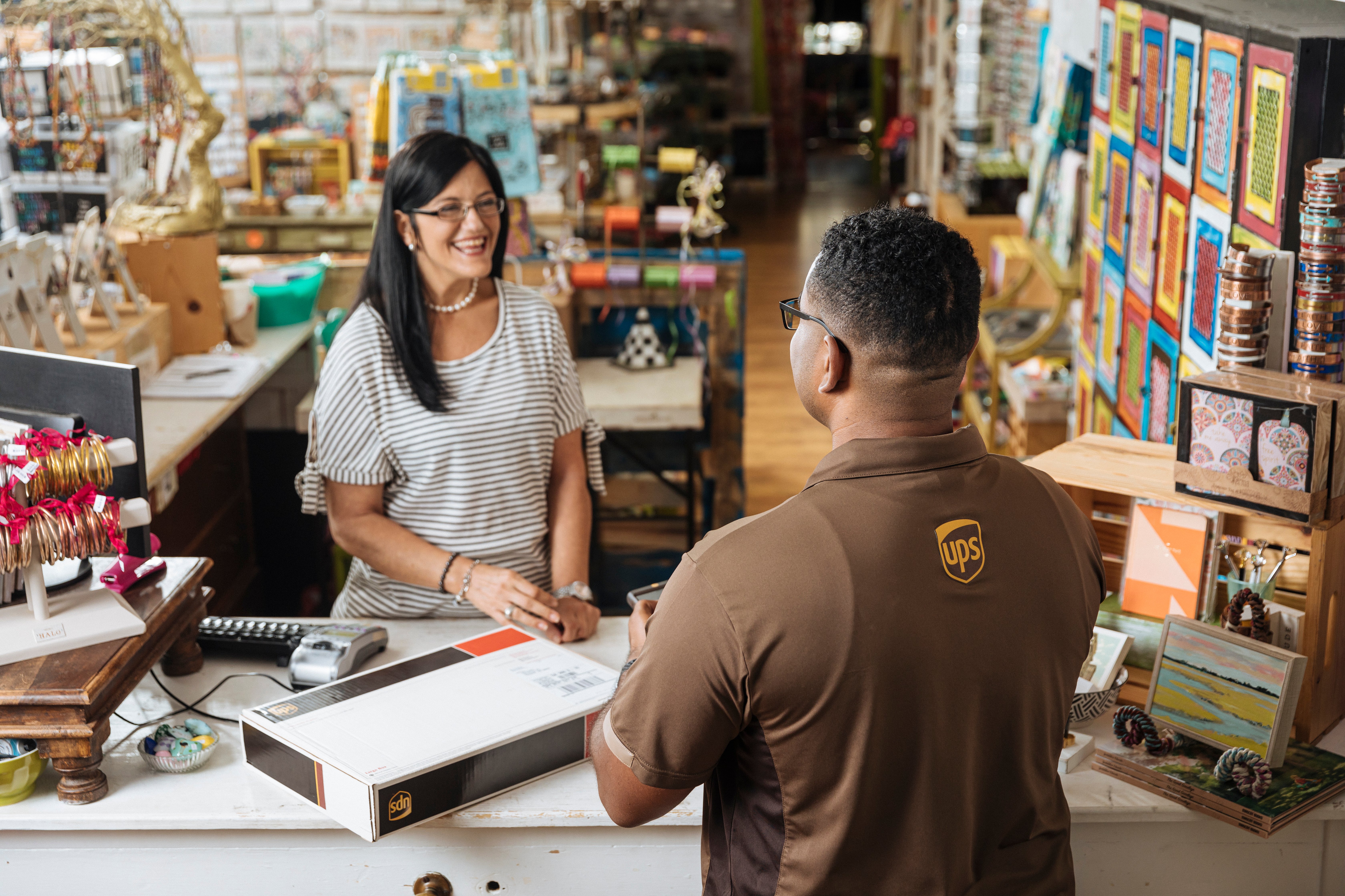 UPS employee serves happy, female customer in a retail setting.