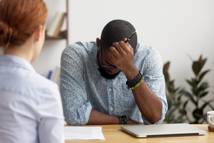 Employee stressed at a desk in a meeting.